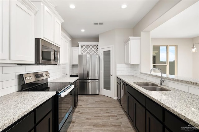 kitchen featuring a sink, visible vents, white cabinetry, appliances with stainless steel finishes, and dark cabinetry