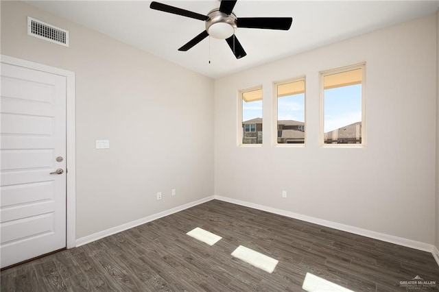 unfurnished room with dark wood-style flooring, visible vents, ceiling fan, and baseboards