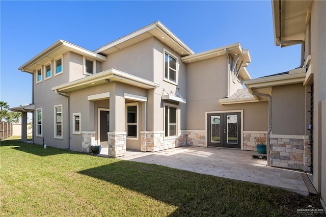 back of house with stone siding, a patio area, a yard, and stucco siding