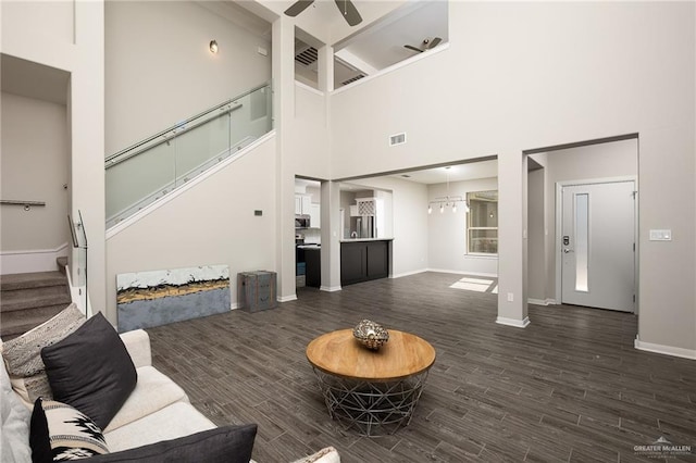 living area featuring dark wood-type flooring, visible vents, stairway, and a ceiling fan