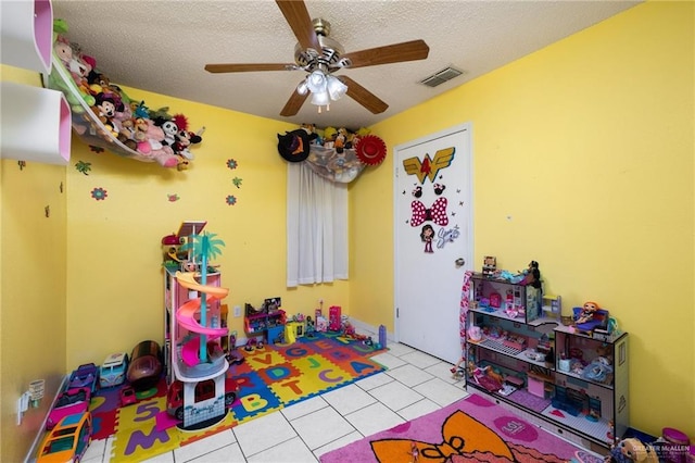 rec room with ceiling fan, light tile patterned floors, and a textured ceiling