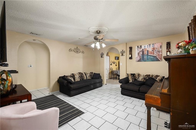 tiled living room with ceiling fan and a textured ceiling