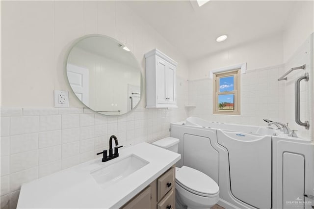 full bath featuring toilet, tile walls, a bath, and vanity