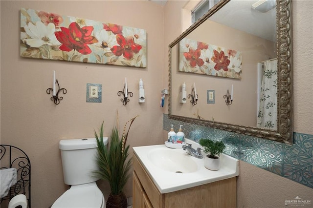 bathroom with vanity, tasteful backsplash, and toilet