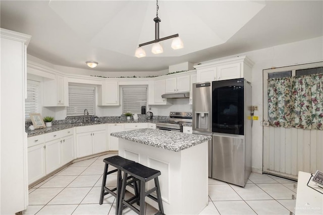 kitchen with a center island, sink, light tile patterned floors, appliances with stainless steel finishes, and decorative light fixtures