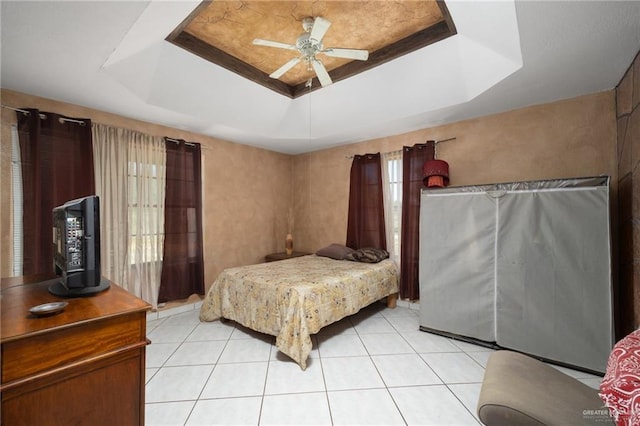 bedroom featuring light tile patterned floors, a raised ceiling, and ceiling fan