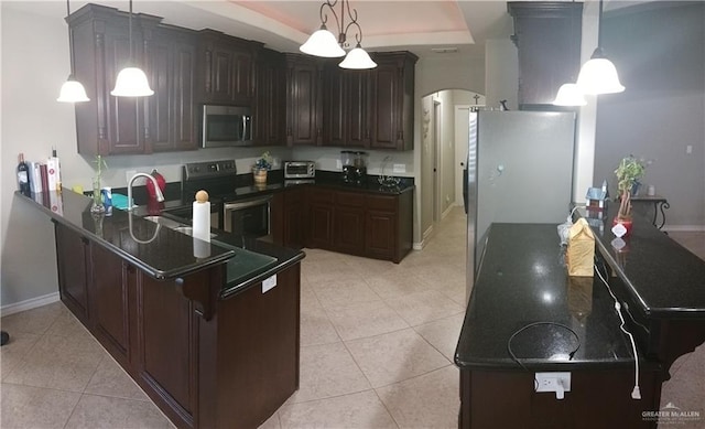 1805 Black Stone St, Edinburg, TX 78542 - kitchen with stainless steel appliances, arched walkways, dark countertops, light tile patterned floors, and a peninsula