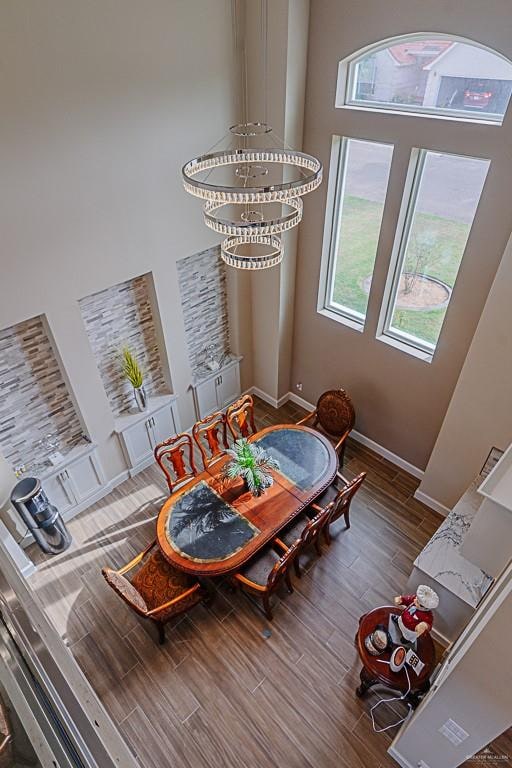 dining room with dark hardwood / wood-style flooring, a high ceiling, and an inviting chandelier