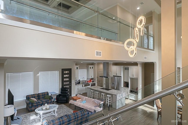 living room with hardwood / wood-style floors, a towering ceiling, and sink