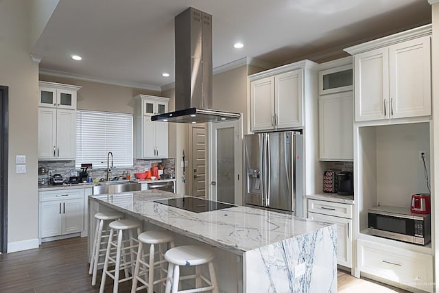 kitchen with a kitchen island, tasteful backsplash, island range hood, white cabinets, and appliances with stainless steel finishes