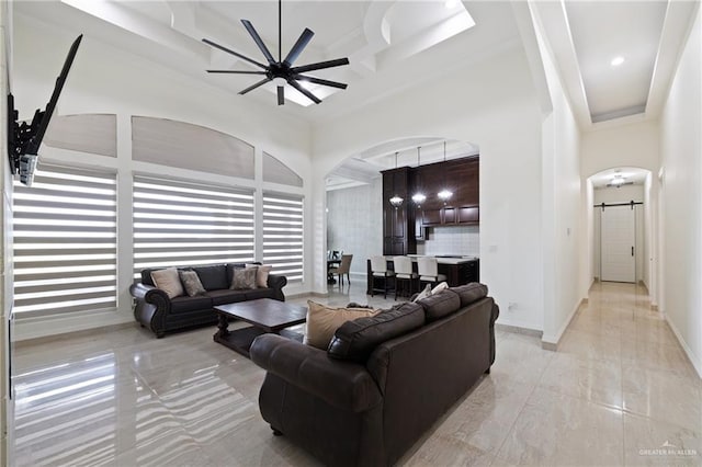 22303 Uresti Rd, Edinburg, TX 78542 - living room with arched walkways, ceiling fan, coffered ceiling, a barn door, and beam ceiling