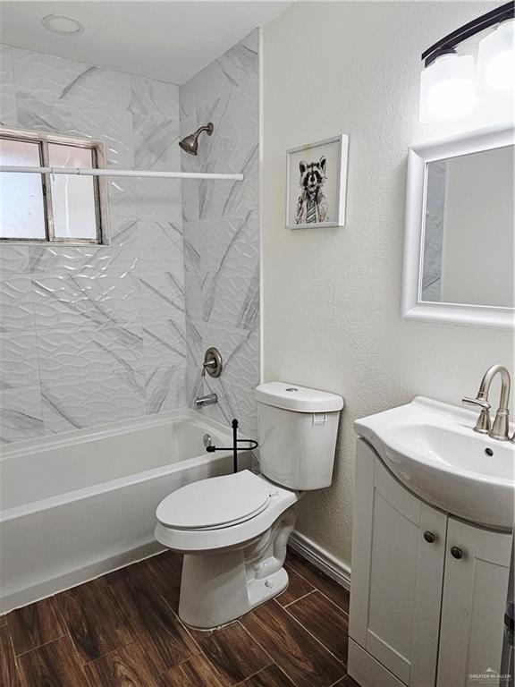 912 Max Dr, Elsa, TX 78543 - bathroom featuring vanity, toilet, shower / bath combination, and wood finished floors