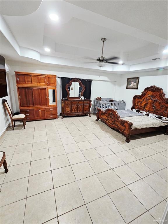 912 Max Dr, Elsa, TX 78543 - bedroom featuring a tray ceiling, light tile patterned flooring, and a ceiling fan
