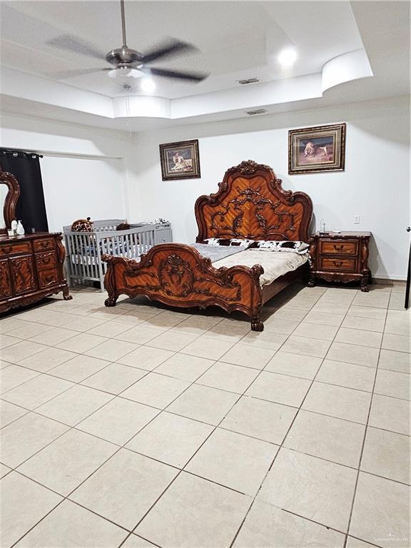 912 Max Dr, Elsa, TX 78543 - bedroom with a tray ceiling, light tile patterned floors, and a ceiling fan