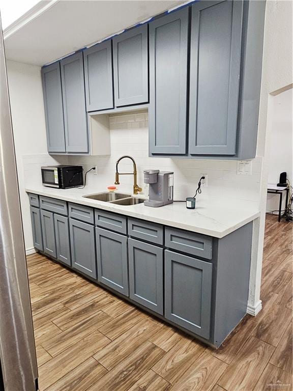 912 Max Dr, Elsa, TX 78543 - kitchen featuring a sink, gray cabinets, light wood-style floors, tasteful backsplash, and light countertops