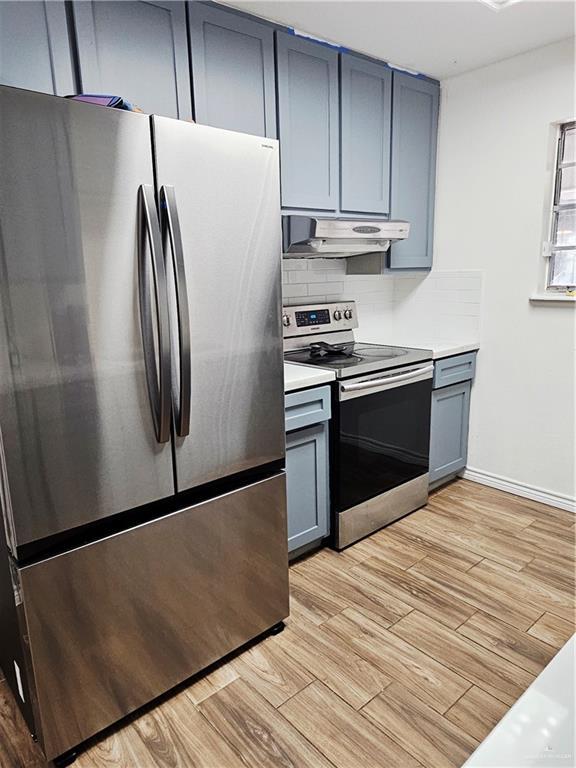 912 Max Dr, Elsa, TX 78543 - kitchen featuring appliances with stainless steel finishes, under cabinet range hood, light wood-type flooring, and gray cabinetry
