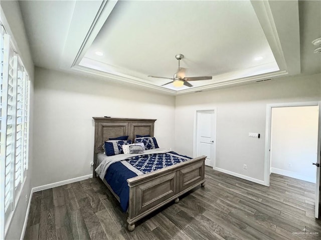 bedroom featuring ceiling fan, dark hardwood / wood-style floors, and a raised ceiling