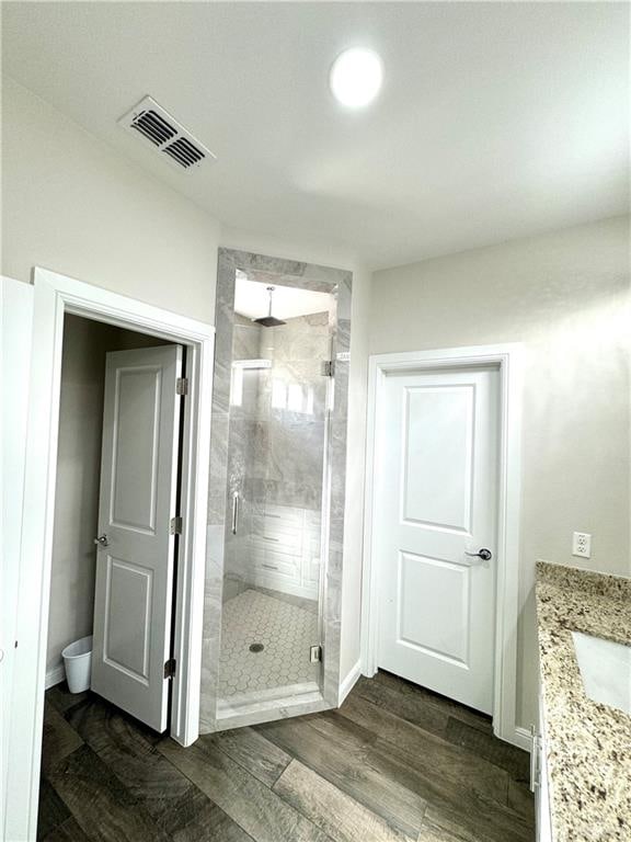 bathroom with wood-type flooring, vanity, and a shower with door