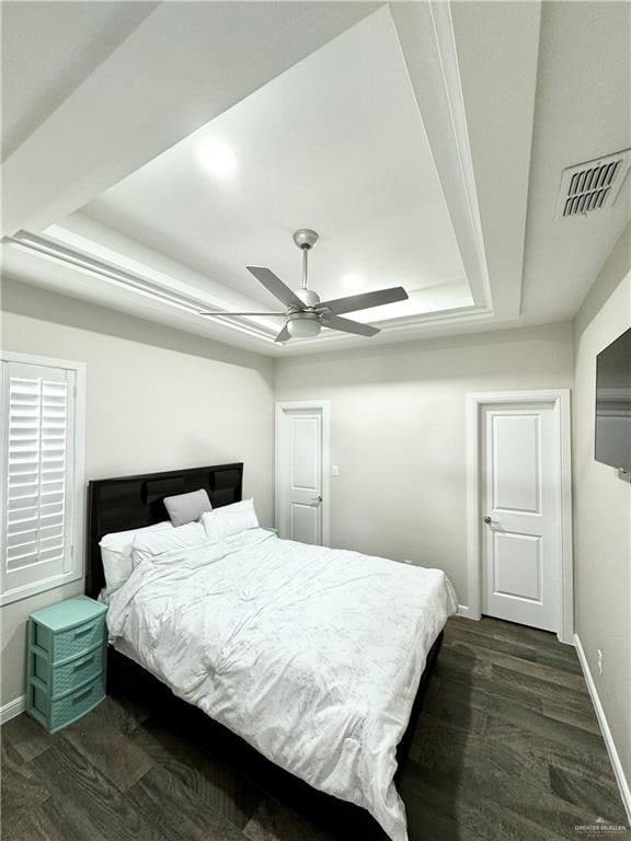 bedroom with a raised ceiling, ceiling fan, and dark hardwood / wood-style flooring