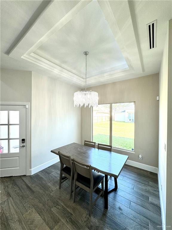 dining area with a raised ceiling, dark hardwood / wood-style floors, and a notable chandelier