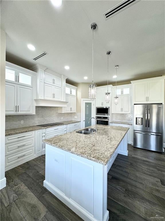 kitchen featuring pendant lighting, white cabinets, sink, an island with sink, and appliances with stainless steel finishes