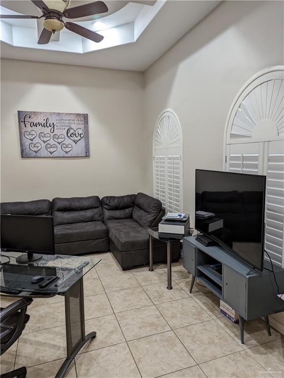 living room featuring ceiling fan, light tile patterned floors, and a towering ceiling