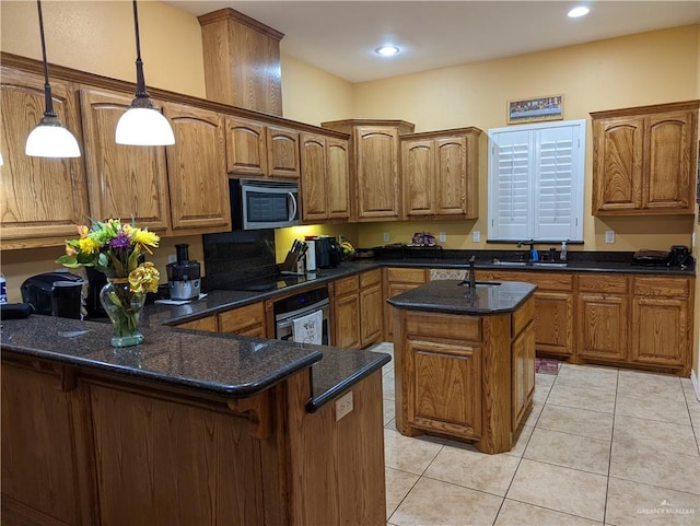 kitchen featuring a kitchen island with sink, dark stone counters, hanging light fixtures, light tile patterned floors, and stainless steel appliances