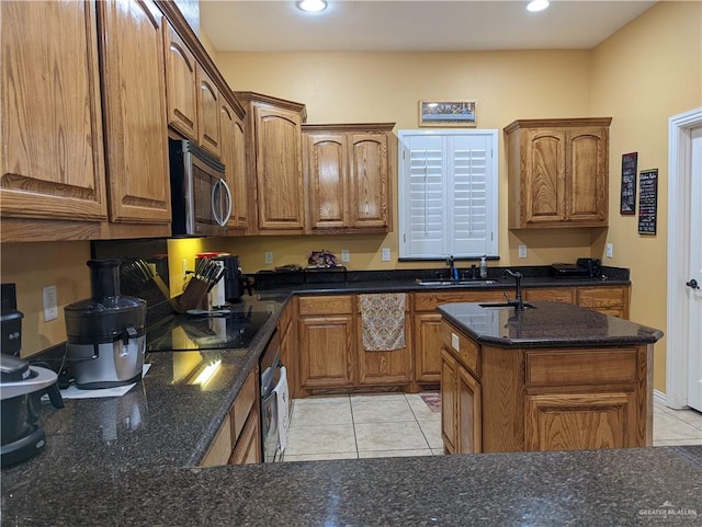 kitchen featuring black electric stovetop, oven, light tile patterned flooring, and sink