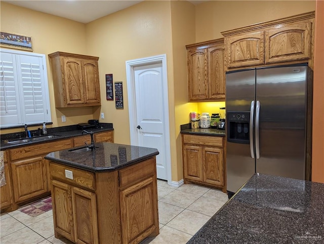 kitchen with stainless steel fridge, sink, light tile patterned flooring, and a kitchen island