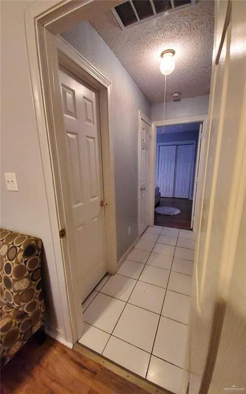 corridor featuring tile patterned floors and a textured ceiling