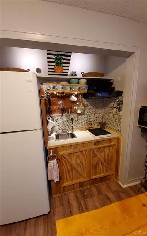 bar featuring electric cooktop, backsplash, wood-type flooring, and white refrigerator