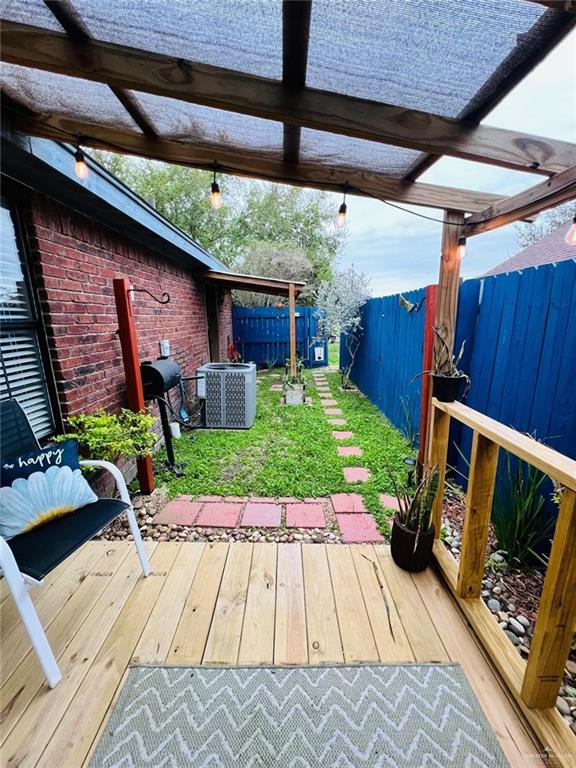 deck with a pergola, a yard, and central air condition unit