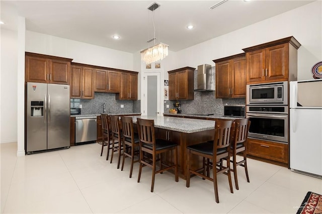 2408 Holland Ave, Edinburg, TX 78539 - kitchen featuring appliances with stainless steel finishes, backsplash, wall chimney range hood, a kitchen island, and a chandelier