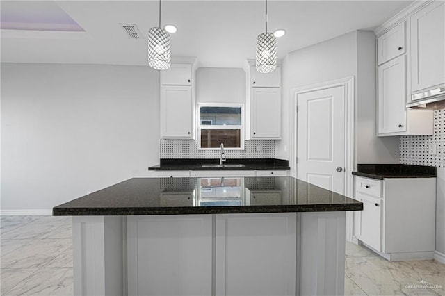 kitchen with a center island, white cabinetry, hanging light fixtures, and sink