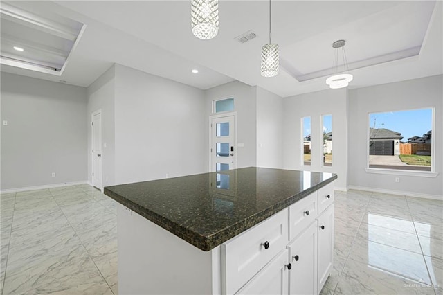 kitchen with pendant lighting, a center island, dark stone counters, a tray ceiling, and white cabinetry