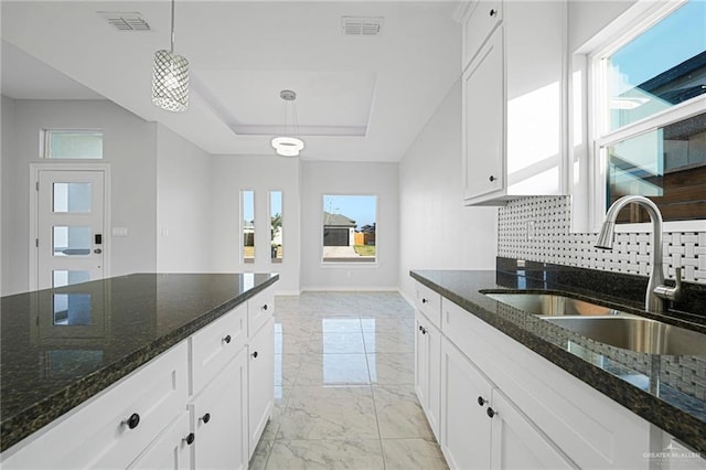 kitchen featuring backsplash, dark stone counters, sink, pendant lighting, and white cabinetry