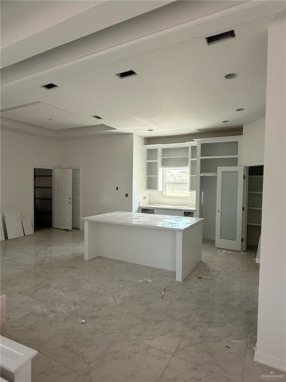 kitchen featuring open shelves, visible vents, marble finish floor, and a kitchen island