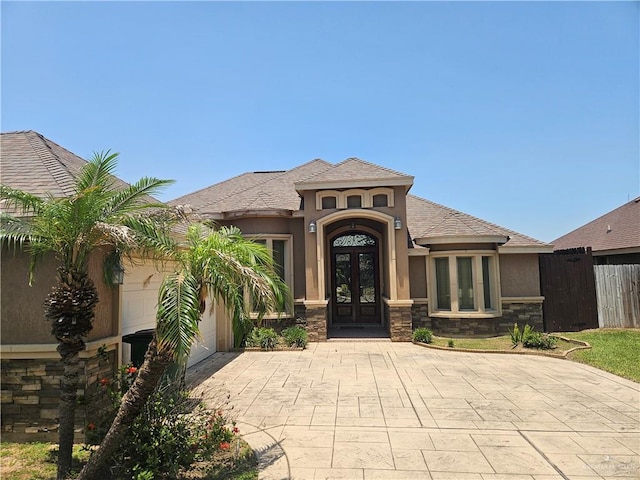 2515 E Q St, Hidalgo, TX 78557 - view of front of home featuring french doors, a garage, stone siding, stucco siding, and decorative driveway