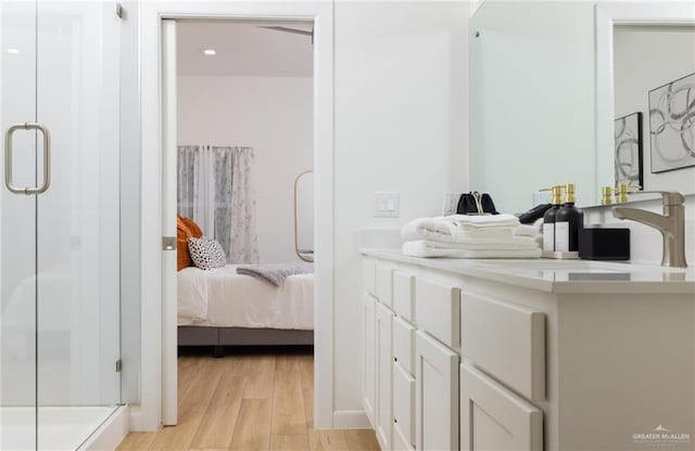 bathroom with hardwood / wood-style flooring, vanity, and an enclosed shower