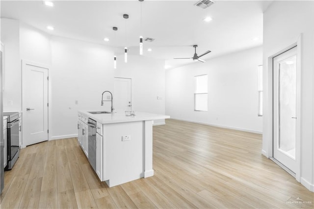 kitchen featuring white cabinetry, sink, stainless steel appliances, decorative light fixtures, and a kitchen island with sink