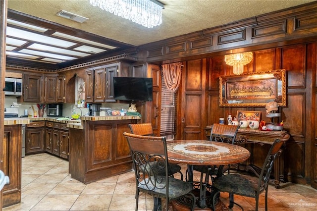 kitchen with a textured ceiling, a notable chandelier, and stainless steel appliances