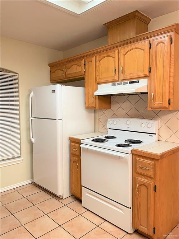 kitchen featuring light tile patterned floors, white appliances, and backsplash