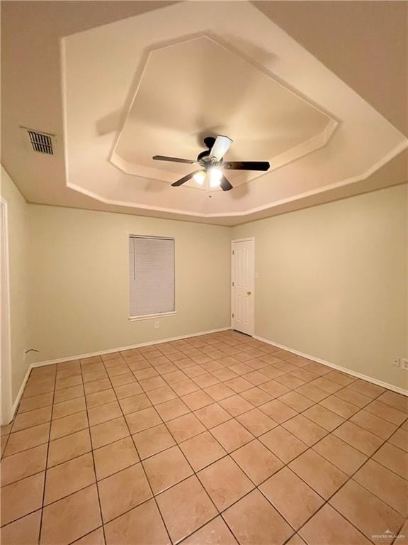 spare room with ceiling fan, light tile patterned floors, and a tray ceiling