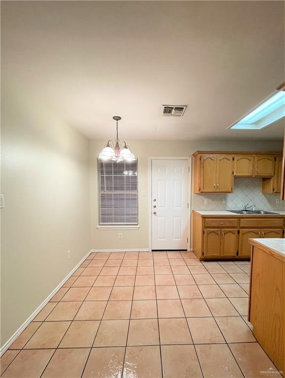 kitchen with decorative light fixtures, light tile patterned flooring, decorative backsplash, and a chandelier