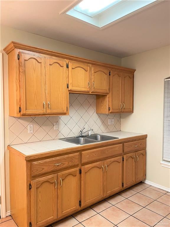 kitchen featuring decorative backsplash, light tile patterned flooring, and a skylight