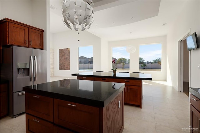 kitchen with an inviting chandelier, light tile patterned floors, stainless steel fridge, and a center island