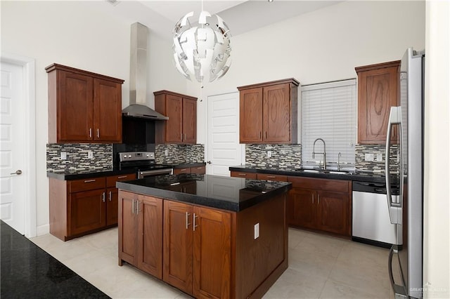 kitchen with wall chimney range hood, sink, appliances with stainless steel finishes, a center island, and a chandelier