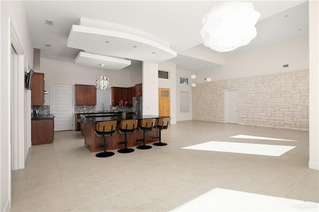 kitchen featuring a breakfast bar area, an inviting chandelier, hanging light fixtures, backsplash, and stainless steel refrigerator with ice dispenser