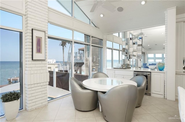 tiled dining space with wine cooler, a water view, and high vaulted ceiling