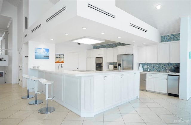 kitchen with a spacious island, white cabinets, light tile patterned flooring, and appliances with stainless steel finishes